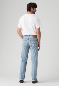 Lichtblauwe denim jeans met een recht model, voorzien van een gestructureerde bruine leren label op de taille en klassieke achterzakken.