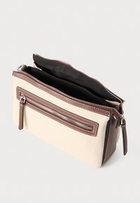 Borsa in tela beige con dettagli in pelle marrone, dotata di una parte superiore con zip e tasca frontale, cuciture bianche e una superficie morbida e textured.