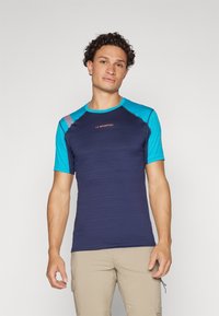 Σκούρο μπλε κοντομάνικο πουκάμισο με ανοιχτό μπλε λεπτομέρειες, με υφή και στρογγυλή λαιμόκοψη. Λογότυπο εμφανίζεται στο στήθος.