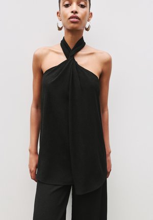 Black sleeveless top with a twisted neckline, featuring a lightweight, textured fabric. Falls loosely, paired with black wide-leg pants.