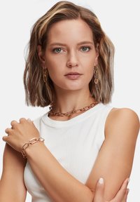 Roze gouden kettingjuwelen, met grote, langwerpige schakels in een gladde afwerking. Inclusief bijpassende oorbellen en een armband.