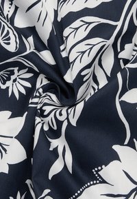 Navy fabric with a white floral pattern, featuring large petals and leaves, smooth texture, and a subtle sheen.
