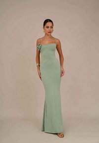 Vestido de evening verde menta, justo, com um detalhe de laço lateral, alças finas e uma saia até ao chão feita de tecido suave.