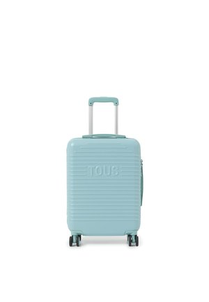 Valise rigide bleu clair avec poignée télescopique, quatre roues pivotantes, rainures horizontales et inscription "TOUS" embossée à l'avant.