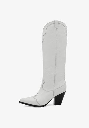 Balta ādas augsta zābaka ar norādītu purngalu, kurai ir viļņota maliņa augšpusē un melns kvadrātsvars. Gluda tekstūra.