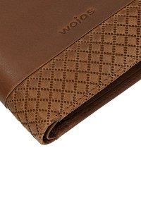 Hoek van een bruine leren portemonnee met het ingeslagen "wojas" logo en een stikselpatroon in diamantvorm.