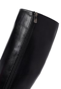 Botte en cuir noir montante avec une fermeture éclair sur le côté et une texture lisse et brillante.