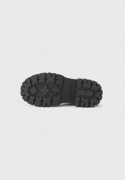 Semelle de botte en caoutchouc noir avec un motif de crampons profonds, incluant des formes carrées et croisées pour une meilleure adhérence. Surface lisse sans marques visibles.