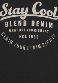 Sudadera negra de algodón con texto gráfico blanco: "Stay Cool", "Blend Denim" y frases estilizadas en varias fuentes y tamaños.