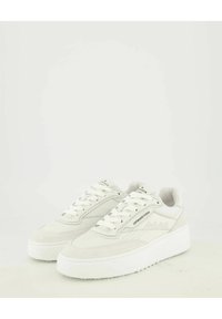 Sneakers bianchi con suola piatta che presentano un mix di materiali lisci e testurizzati, accenti grigi discretamente visibili e dettagli perforati sui lati.