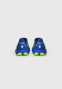 Des chaussures de sport bleues avec une tige en maille texturée, une semelle en caoutchouc verte, des accents noirs et un logo près du talon. La vue arrière montre clairement les éléments de design.