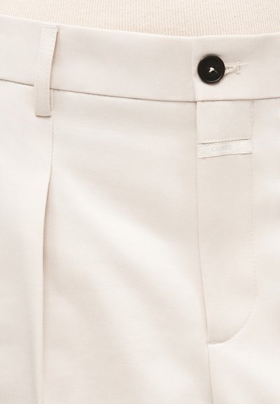 Vaaleanbeiget housut, joissa on sileä, teksturoitu pinta. Housuissa on nappikiinnitys, sivutasku ja huomaamaton merkkilappu.