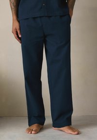 Sötétkék nadrág texturált anyagból, laza fit, egyenes lábakkal. Rugalmas derékpánttal rendelkezik, és nincs látható fém vagy zseb.