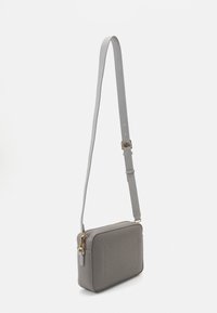 Sac en cuir gris de type bandoulière, de forme rectangulaire, avec une texture lisse, une bandoulière réglable et des accents en métal doré.