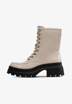 Stivaletto beige alto con lacci, suola piattaforma nera spessa con battistrada profondo, texture in pelle liscia e punta arrotondata.