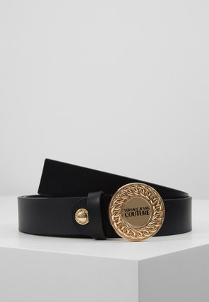 Ceinture en cuir noir avec boucle ronde dorée comportant un motif chaîne et le texte « Versace Jeans Couture » au centre.