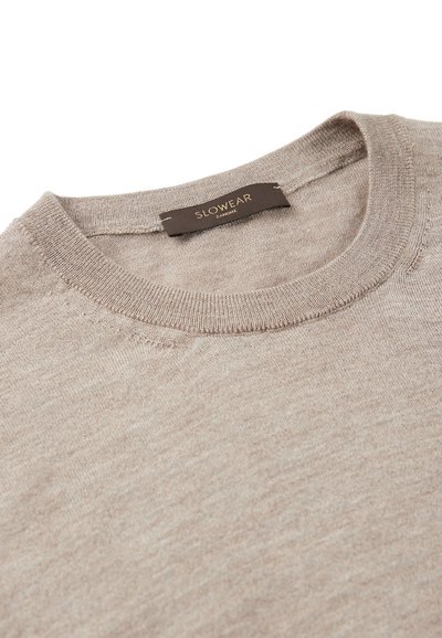 Suéter de punto en color beige con escote redondo; fabricado con una tela suave; presenta una etiqueta que dice "SLOWEAR ZANONE". Textura fina en toda la prenda.