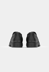 Pantofi din piele neagră cu textură netedă, perforații decorative, vârf rotund și toc mic. Design simplu, fără culori sau accente suplimentare.