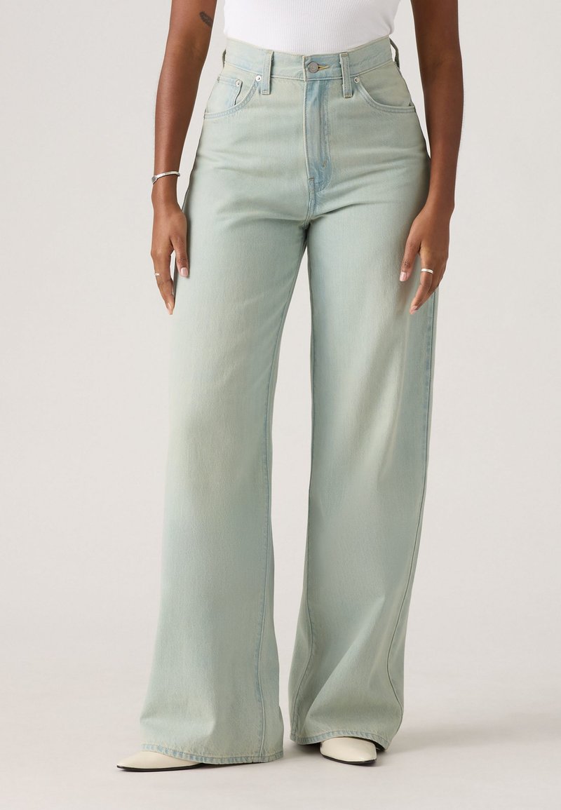 Light green high-waisted wide-leg jeans made of soft denim. Features belt loops, front pockets, and subtle fading. Smooth texture.