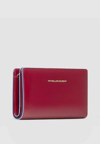 Cartera de cuero burdeos con detalles en azul, forma rectangular compacta. Presenta un logotipo en dorado, textura suave y costuras visibles.