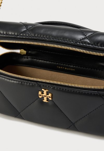 Μαύρο καπιτονέ δερμάτινο τσαντάκι με χρυστό φερμουάρ μισάνοιχτο, που αποκαλύπτει μπεζ εσωτερικό και χρυσό λογότυπο Tory Burch μπροστά.