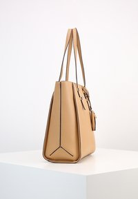 Sac fourre-tout en cuir tan avec un design structuré, doté de deux poignées, de coutures contrastées et d'un petit détail en pendentif.