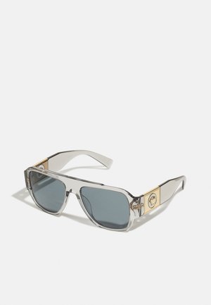 Sonnenbrille mit einem klaren Kunststoffrahmen, grauen getönten Gläsern und einem goldenen Metallemblem an den Bügeln. Quadratdesign mit glatter Textur.