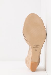 Scarpa con tacco alto in suede beige con suola in gomma liscia. L'etichetta indica "JONAK PARIS MADE IN PORTUGAL" e la misura "37."