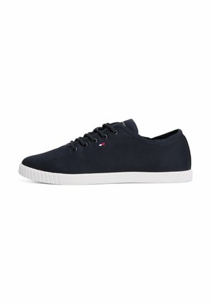 Granatowy niski sneaker z czarnymi sznurowadłami, białą gumową podeszwą i małym czerwono-biało-niebieskim logo z boku.
