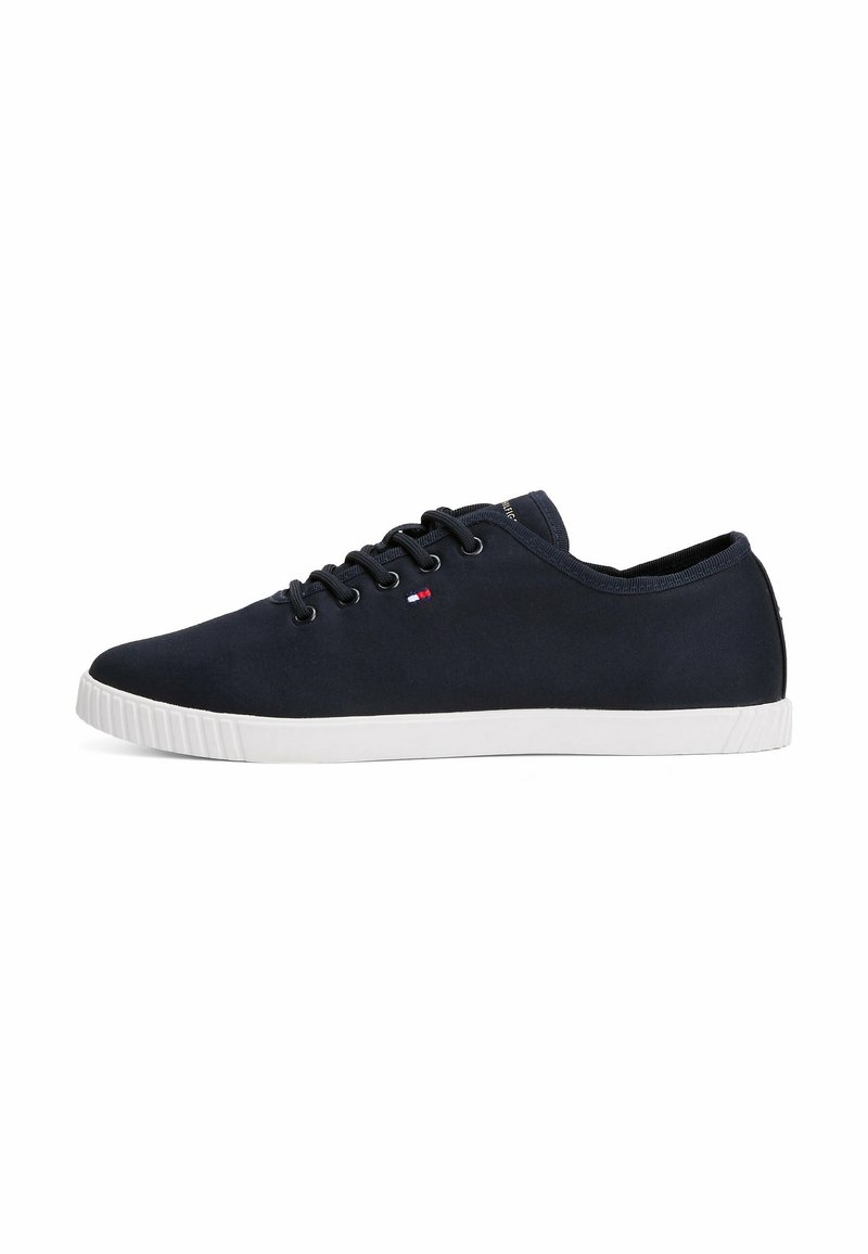 Baskets basses bleu marine avec lacets noirs, semelle en caoutchouc blanche et petit logo rouge, blanc et bleu sur le côté.