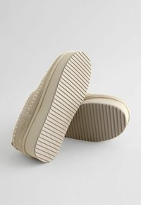 Beige sneakers med et tekstureret stofoverdel og en tyk, ribbet gummisål. Synlige syninger og en glat, let nuanceret finish.