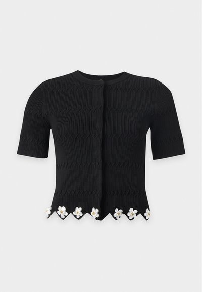Cardigan noir en maille à manches courtes avec motif texturé et ornements floraux blancs le long de l'ourlet festonné.