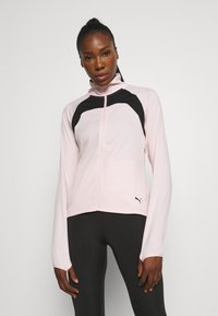 Hellrosa Zip-Up-Jacke mit schwarzen Akzenten, hohem Kragen und langen Ärmeln. Verfügt über eine glatte Textur und das Puma-Logo auf der unteren rechten Seite.
