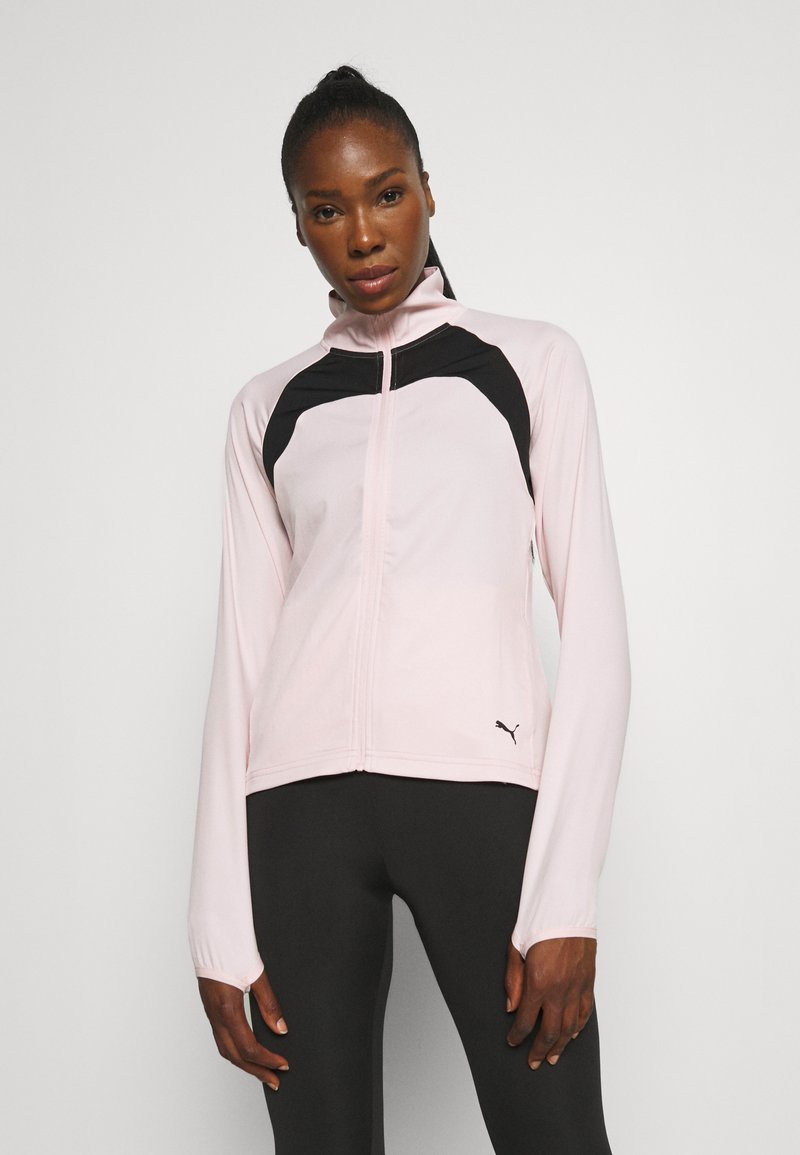 Hellrosa Zip-Up-Jacke mit schwarzen Akzenten, hohem Kragen und langen Ärmeln. Verfügt über eine glatte Textur und das Puma-Logo auf der unteren rechten Seite.