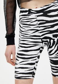 Zwart-witte, met zebraprint-gepatenteerde fietsbroek gemaakt van rekbaar materiaal, met een getailleerd ontwerp en een gladde textuur.