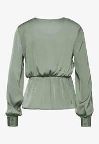 Blusa a maniche lunghe in satin verde chiaro con vita arricciata, texture liscia e polsini con bottoni. La schiena presenta un collo a barca.