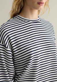 Felpa a righe con strisce orizzontali blu navy e bianche, scollo rotondo, vestibilità ampia, in morbido cotone e dettagli di cucitura in vista.