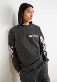 Black long-sleeve t-shirt made of cotton, featuring a graphic print on sleeves, including compass and colorful accents. Casual fit.