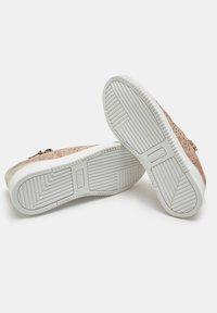 Sneakers con una parte superiore in suede beige, design perforato, suole in gomma crema, motivo di battistrada testurizzato e dettaglio con zip sul lato.