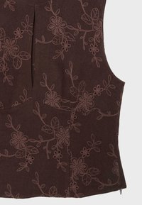 Haut marron sans manches avec motifs floraux et feuilles brodés dans un fil assorti, avec un pli à l'avant et un détail fermeture éclair sur le côté.