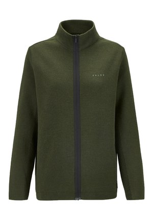 Donkergroene zip-up jas van textuurstof, met hoge kraag en zijzakken, gecombineerd met zwarte broek en bruine wandelschoenen.