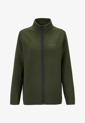 Donkergroene zip-up jas van textuurstof, met hoge kraag en zijzakken, gecombineerd met zwarte broek en bruine wandelschoenen.