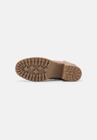 Semelle en caoutchouc marron avec des profondeurs de sculpture et un motif robuste. Présente une étiquette de taille "37" embossée sur le côté. Matériau durable et surface texturée.