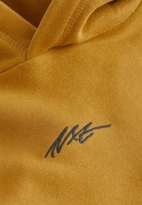 Hoodie jaune moutarde en tissu doux, avec une texture subtile. Un logo brodé bleu foncé est situé à l'avant.