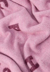 Rózsaszín szövet lágy textúrával, finom mintával és sötétebb rózsaszín díszítéssel. Az anyag könnyűnek és kényelmesnek tűnik.