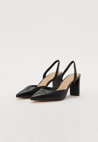 Black leather slingback heels with a pointed toe and block heel. Smooth texture and minimalistic design with a tan insole.
