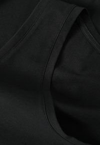 Gros plan d’un tissu noir plié avec des coutures visibles et une texture lisse, mettant en valeur les coutures et les bords.