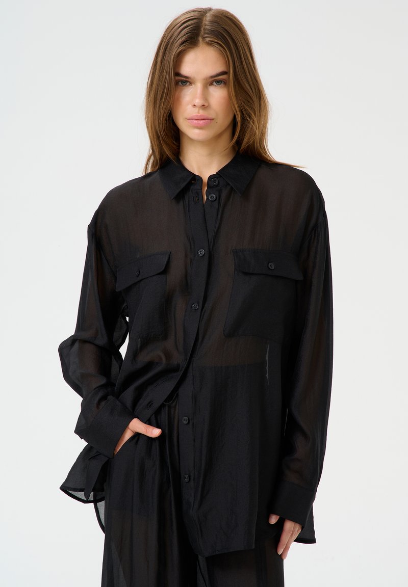 Black sheer button-up shirt with two chest pockets, long sleeves, and a relaxed fit, displaying a lightweight, translucent fabric.