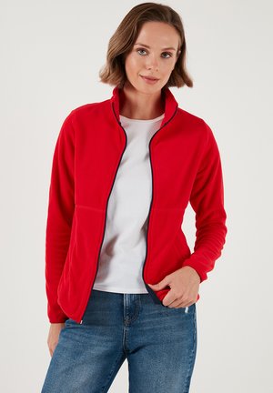 Jachetă roșie din fleece cu guler înalt, față cu fermoar și accente bleumarin. Textură moale și design ajustat, cu buzunare laterale.