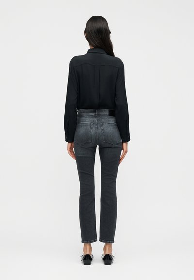 Μαύρο πουκάμισο με μακριά μανίκια σε συνδυασμό με εφαρμοστά σκουρόχρωμα γκρι τζιν. Το τζιν διαθέτει ψηλή μέση και διακριτικές ραφές. Μαύρα παπούτσια ολοκληρώνουν την εμφάνιση.